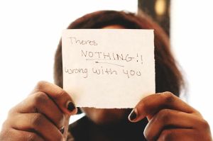 Woman Holding Up a Note That Says There's Nothing Wrong With You