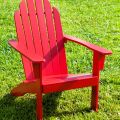 Red Adirondack Chair On A Grass Lawn